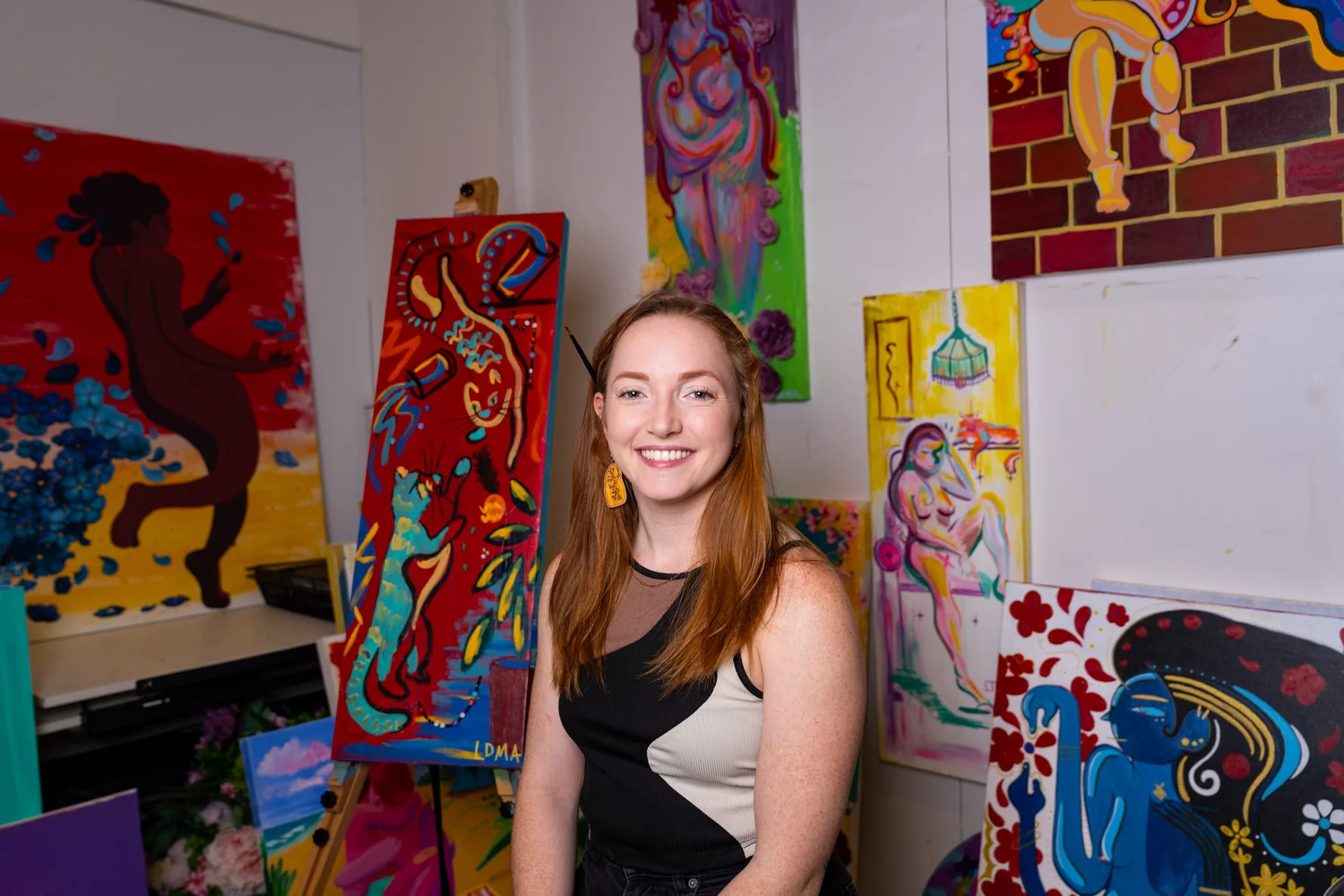 LDMA in her studio surrounded by her colorful artwork